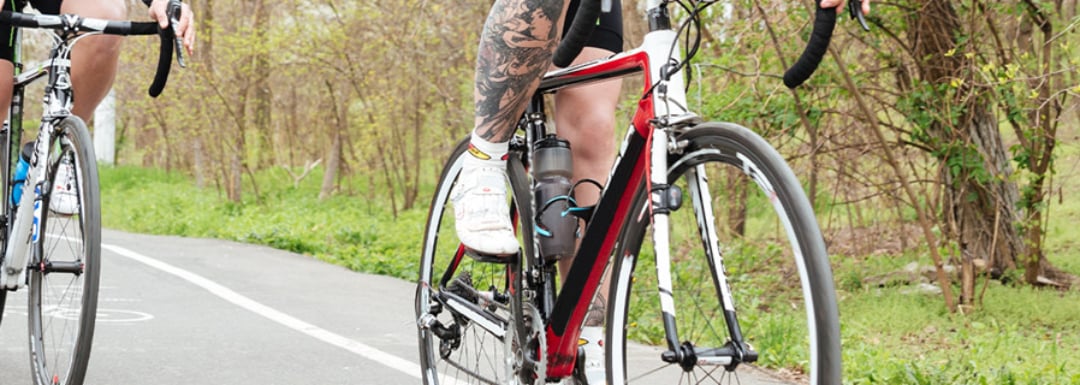 Close-up shot of a mans leg peddling a red bicycle.