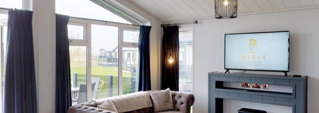 Holiday home living area featuring large windows looking out onto terrace area.